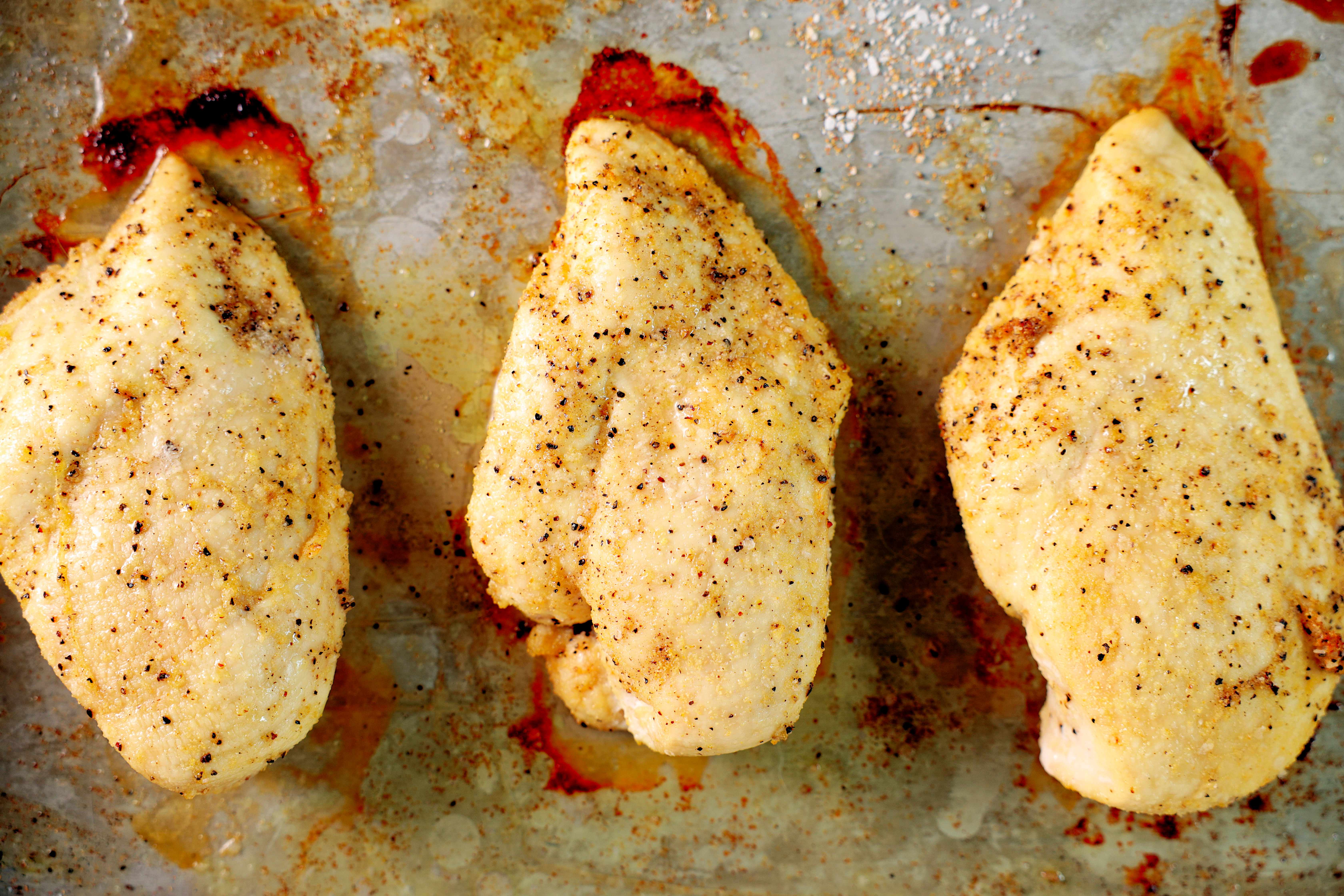 An overhead shot of three cooked chicken breast on a baking sheet. 