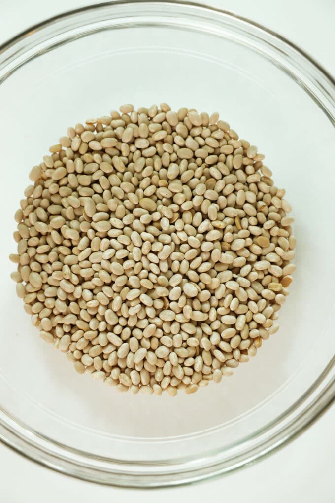 Dried navy beans in a clear, glass bowl.