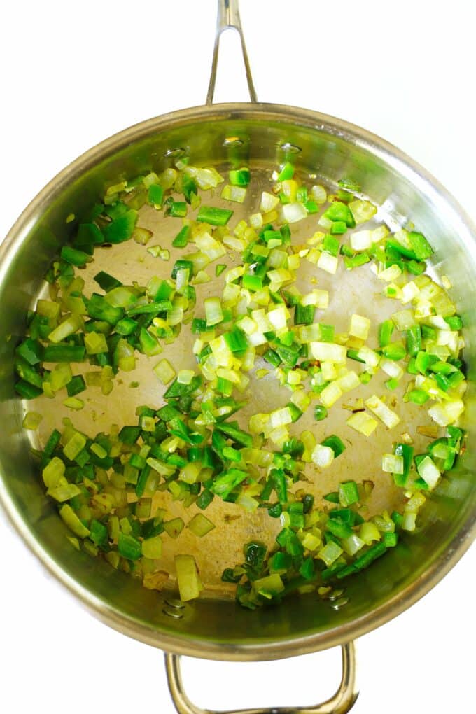 Diced onion and jalapeño cooking in a skillet.