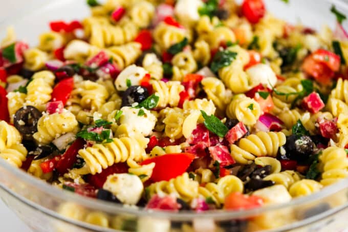 A big, glass mixing bowl full of Italian Pasta Salad.