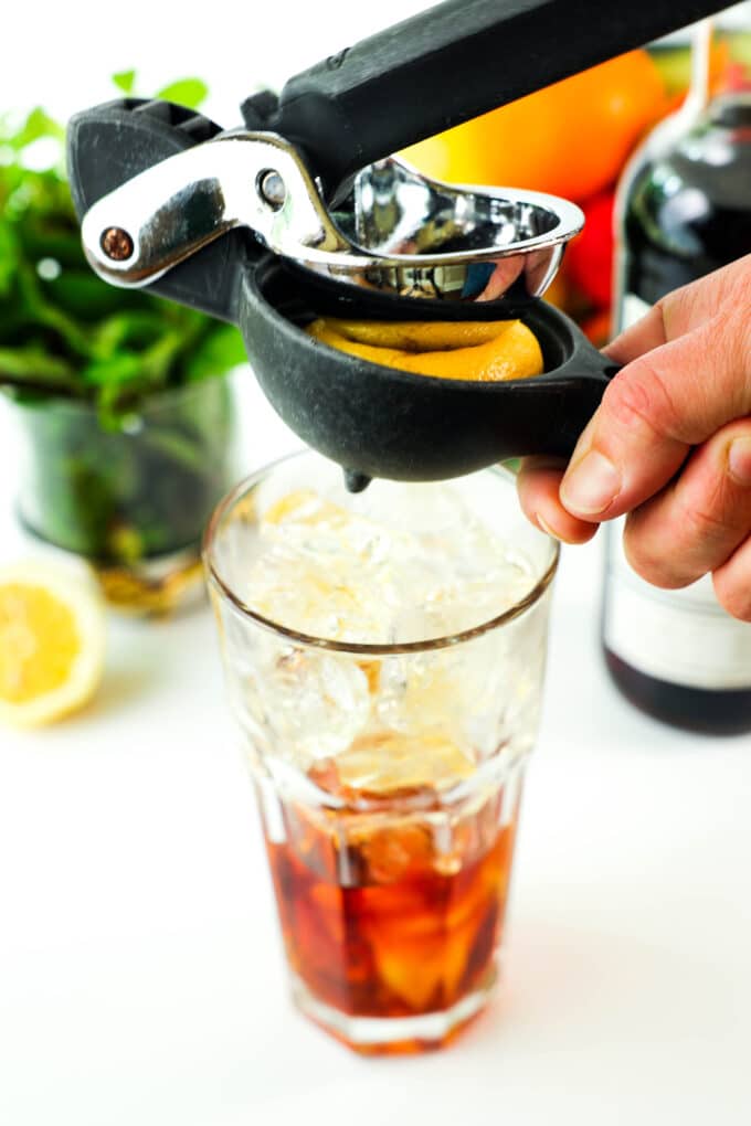 Half a lemon being juiced into the glass with a citrus press.