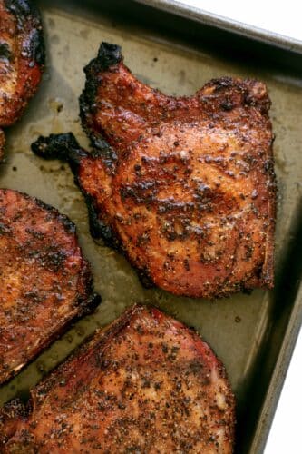 An overhead view of Smoked Pork Chops on a sheet pan. They are crispy around the edges.