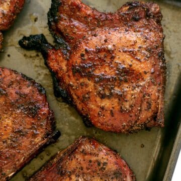 An overhead view of Smoked Pork Chops on a sheet pan. They are crispy around the edges.