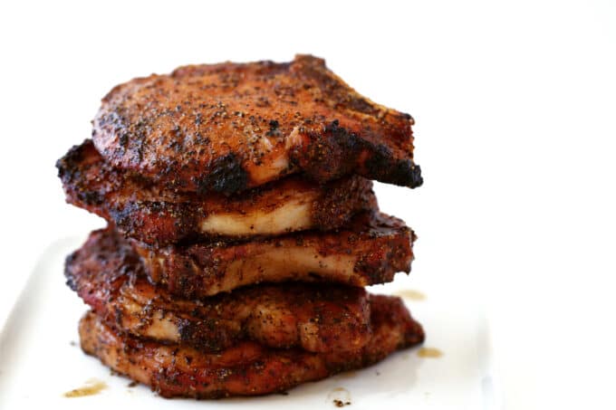 A stack of several Smoked Pork Chops on a white plate.
