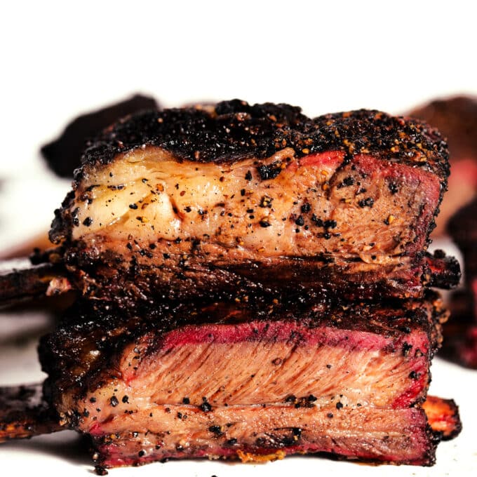 A close up of two Beef Ribs, stacked. The outer layer is blackened but the middle is a little pink.