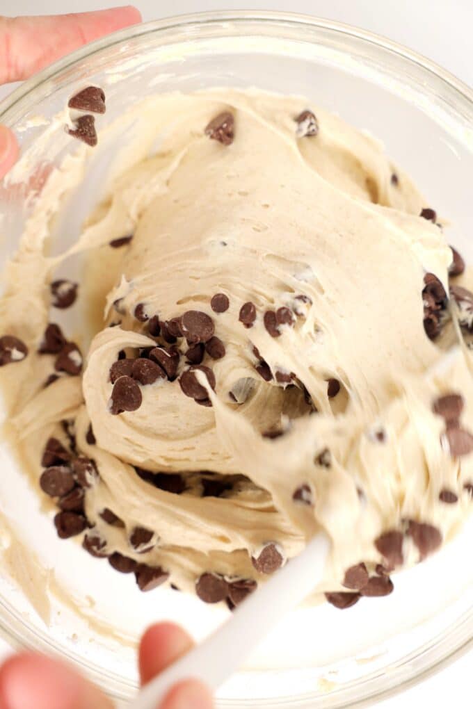 A hand using a silicon spatula to fold chocolate chips into the Cookie Dough Dip.