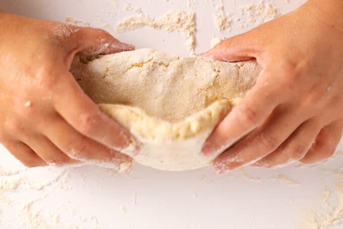 Hands folding biscuit dough into layers.