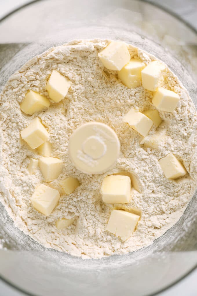 Cubed butter sprinkled on top of the dry ingredients in a food processor.