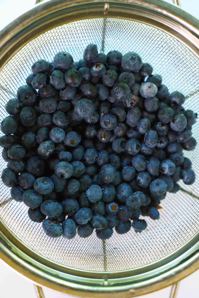 An overhead view of fresh blueberries in a mesh strainer.