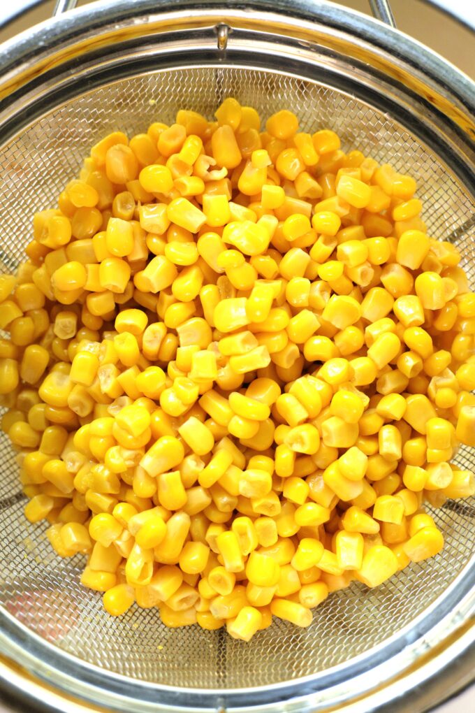 bright yellow sweet corn kernels in a colander. 
