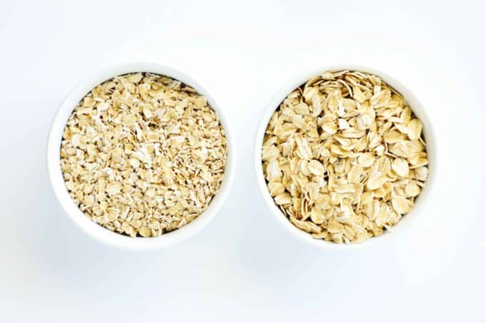 Two bowls of oats sitting side by side. One has rolled oats and the other quick oats, which are much finer.