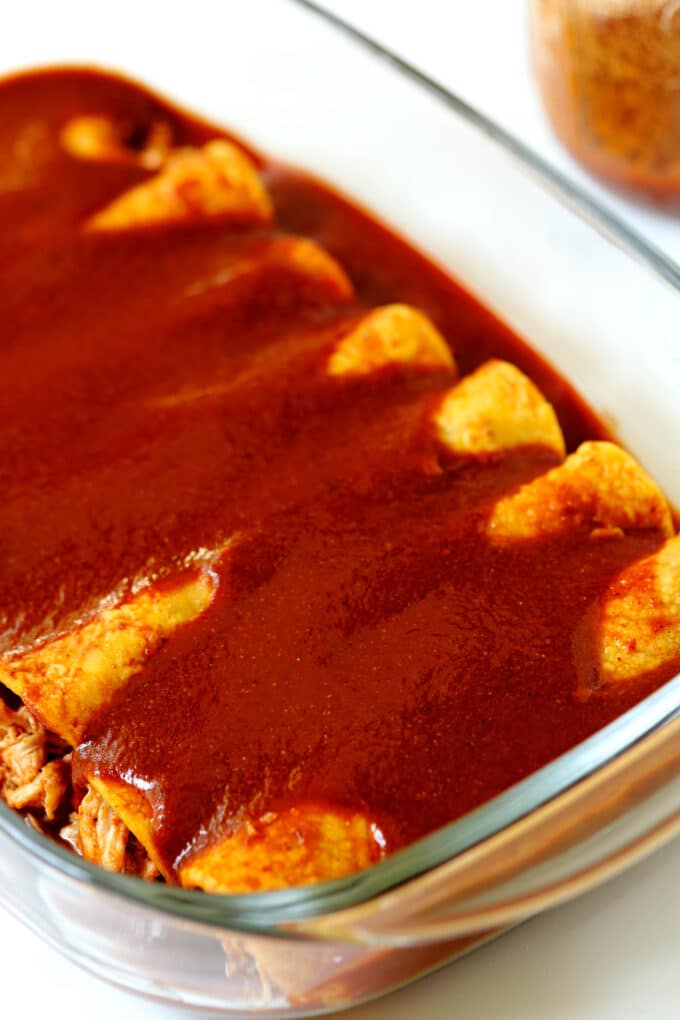 A glass pan of enchiladas with Homemade Enchilada Sauce poured over the top.