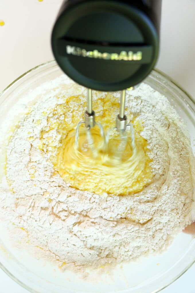 The flour mixture being mixed into the wet ingredients with a hand mixer.