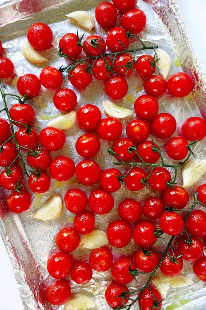 An overhead look at a pan of uncooked cherry tomatoes and cloves of garlic.