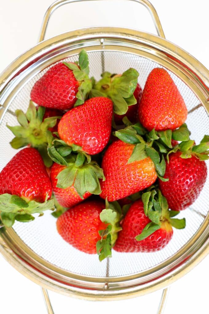 An overhead look at a strainer of fresh strawberries.