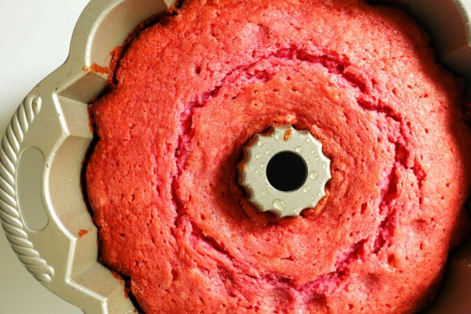 An overhead view of a Strawberry Pound Cake fresh out of the oven and still in the bundt pan. The top is a deep pink color.