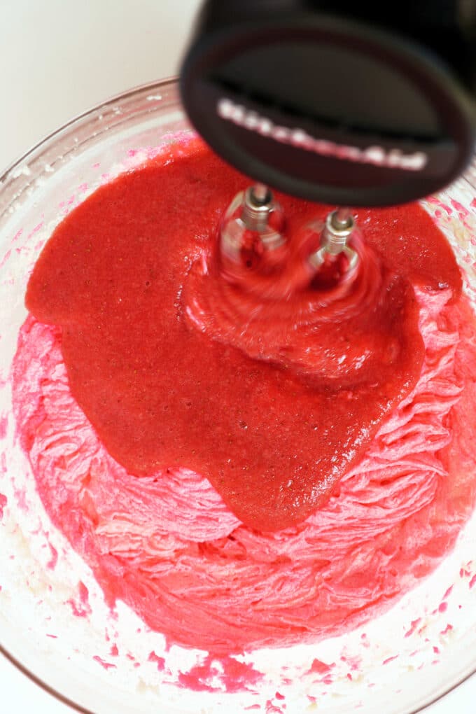 Strawberry purée being mixed into the wet ingredients with a hand mixer.