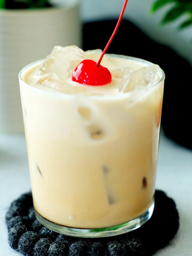 A Colorado Bulldog cocktail in a rocks glass with a bright red cherry on top.