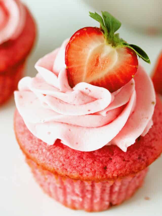 An overhead shot of a single cupcake with a fresh sliced strawberry on top.