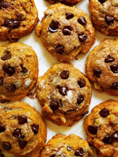 An overhead look at a batch of Pumpkin Chocolate Chip Cookies on a white surface.