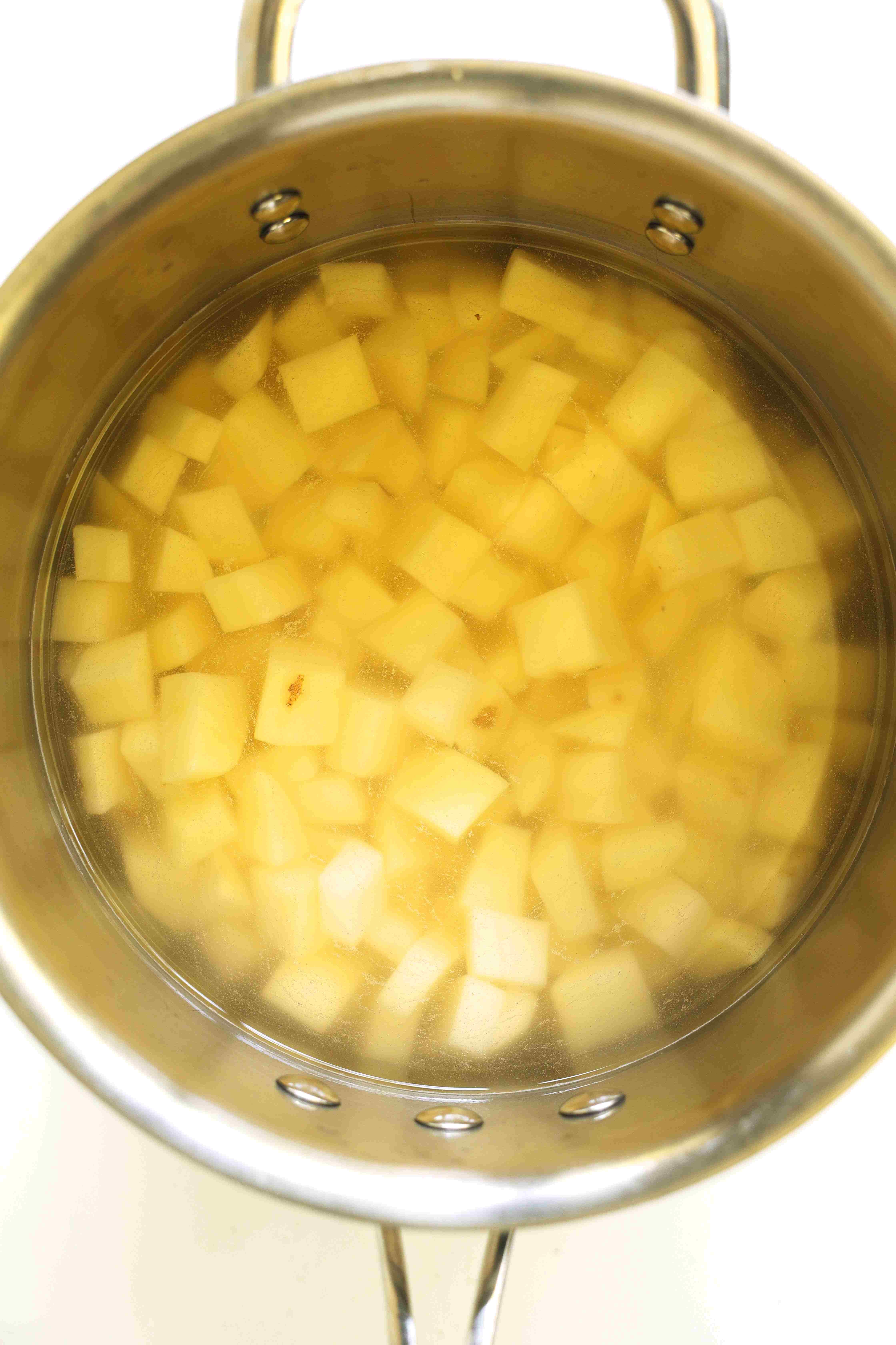 Diced potatoes covered in water, in a pot.