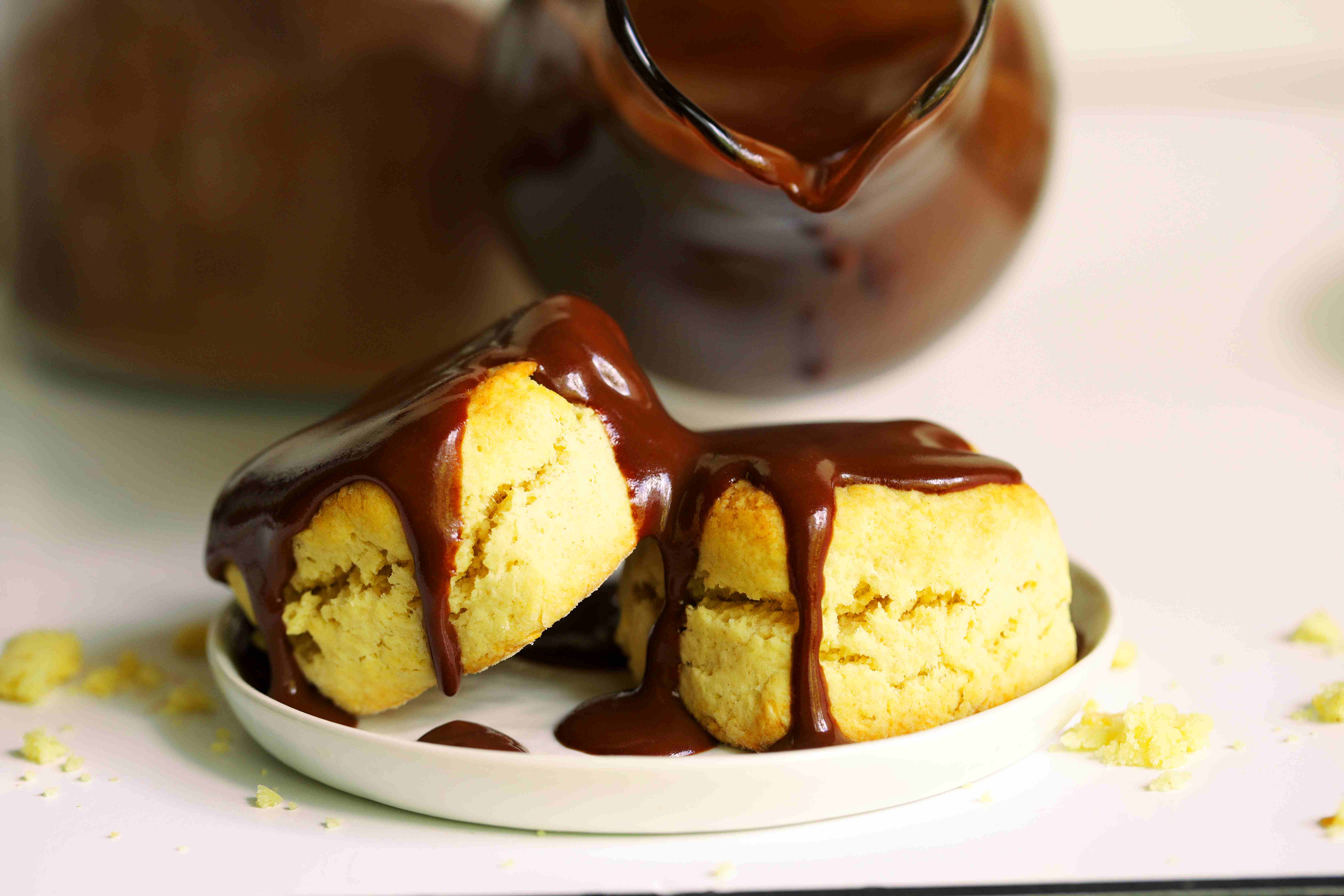 Two biscuits on a white plate drizzled with Chocolate Gravy