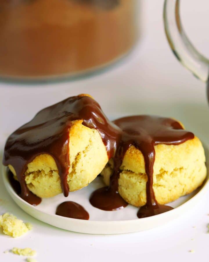 Two biscuits on a white plate drizzled with Chocolate Gravy