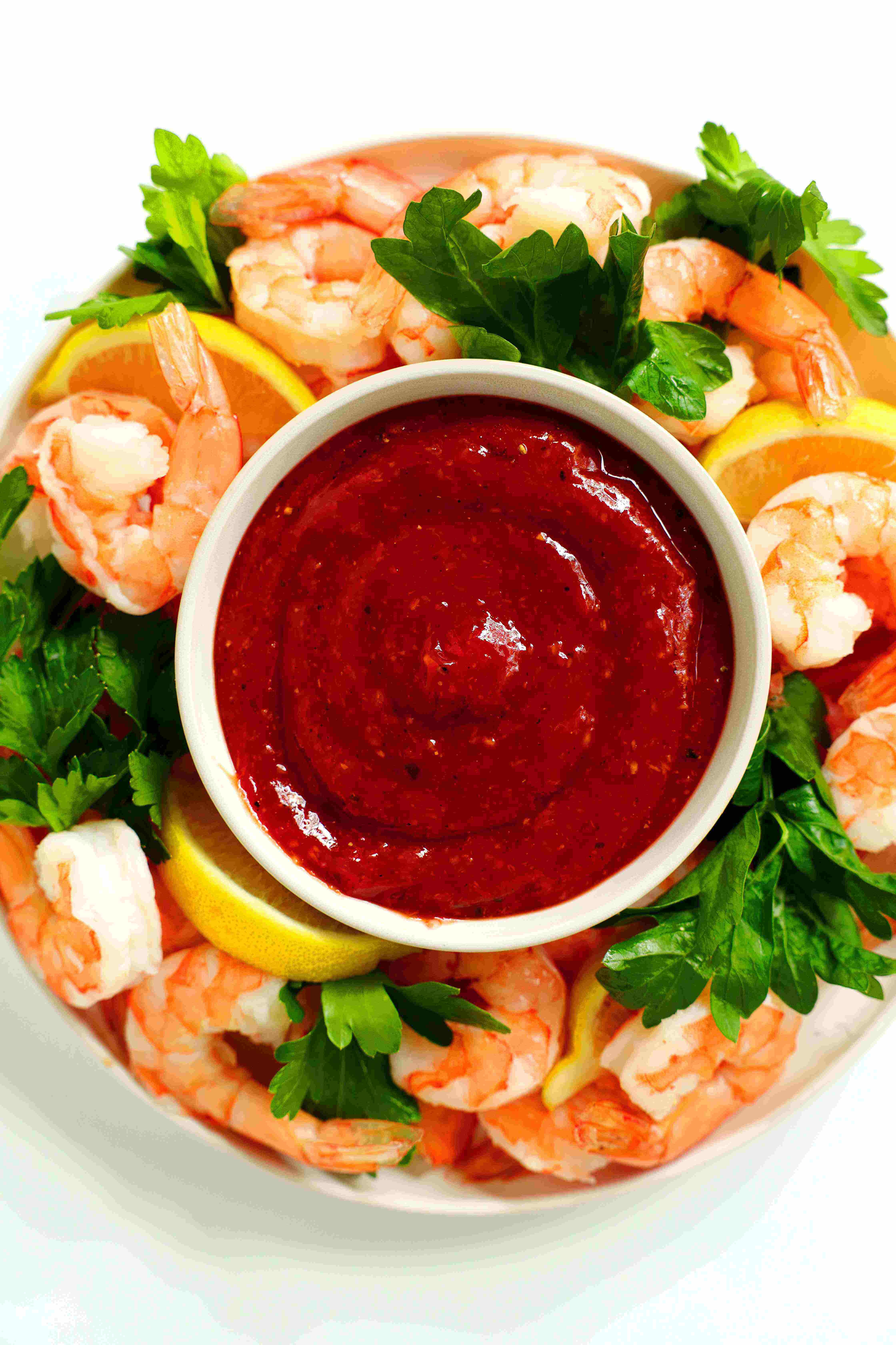 Shrimp Cocktail Sauce Recipe on a platter with shrimp, cilantro, and lemon wedges