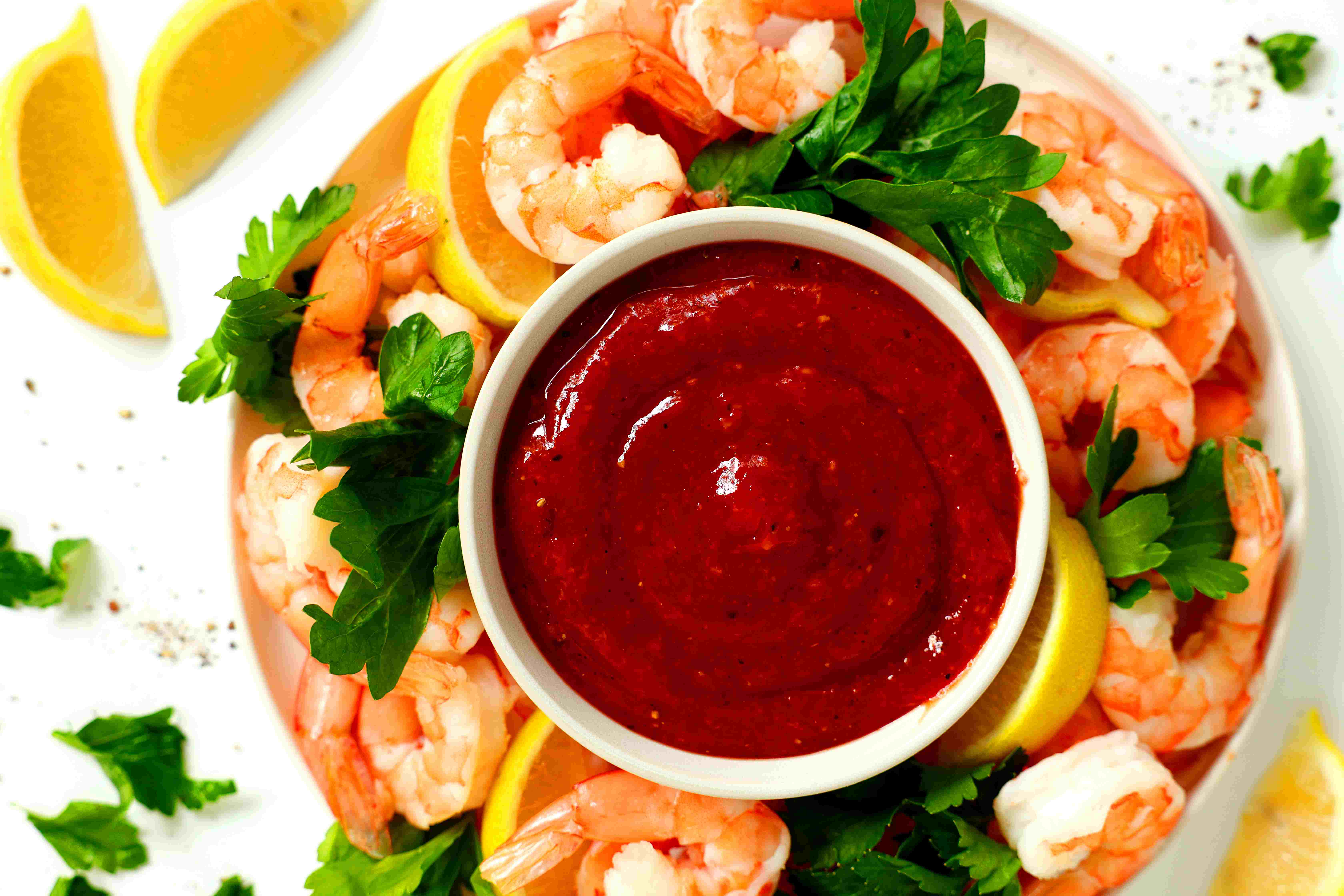 Shrimp Cocktail Sauce Recipe on a platter with shrimp, cilantro, and lemon
