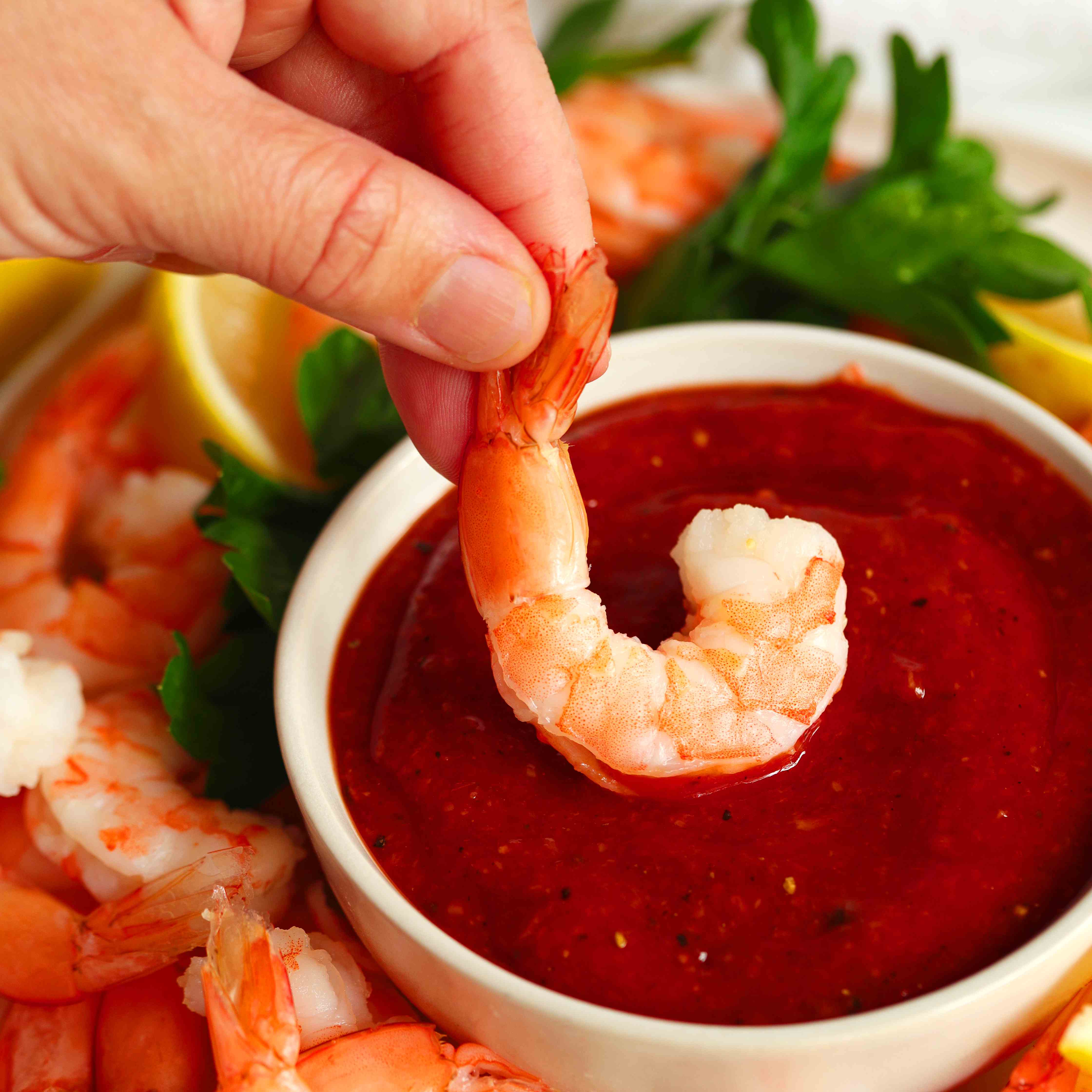 Shrimp being dipped in cocktail sauce