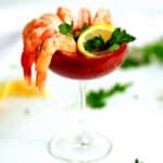 Shrimp cocktail with shrimp, lemon, and cilantro in a cocktail glass