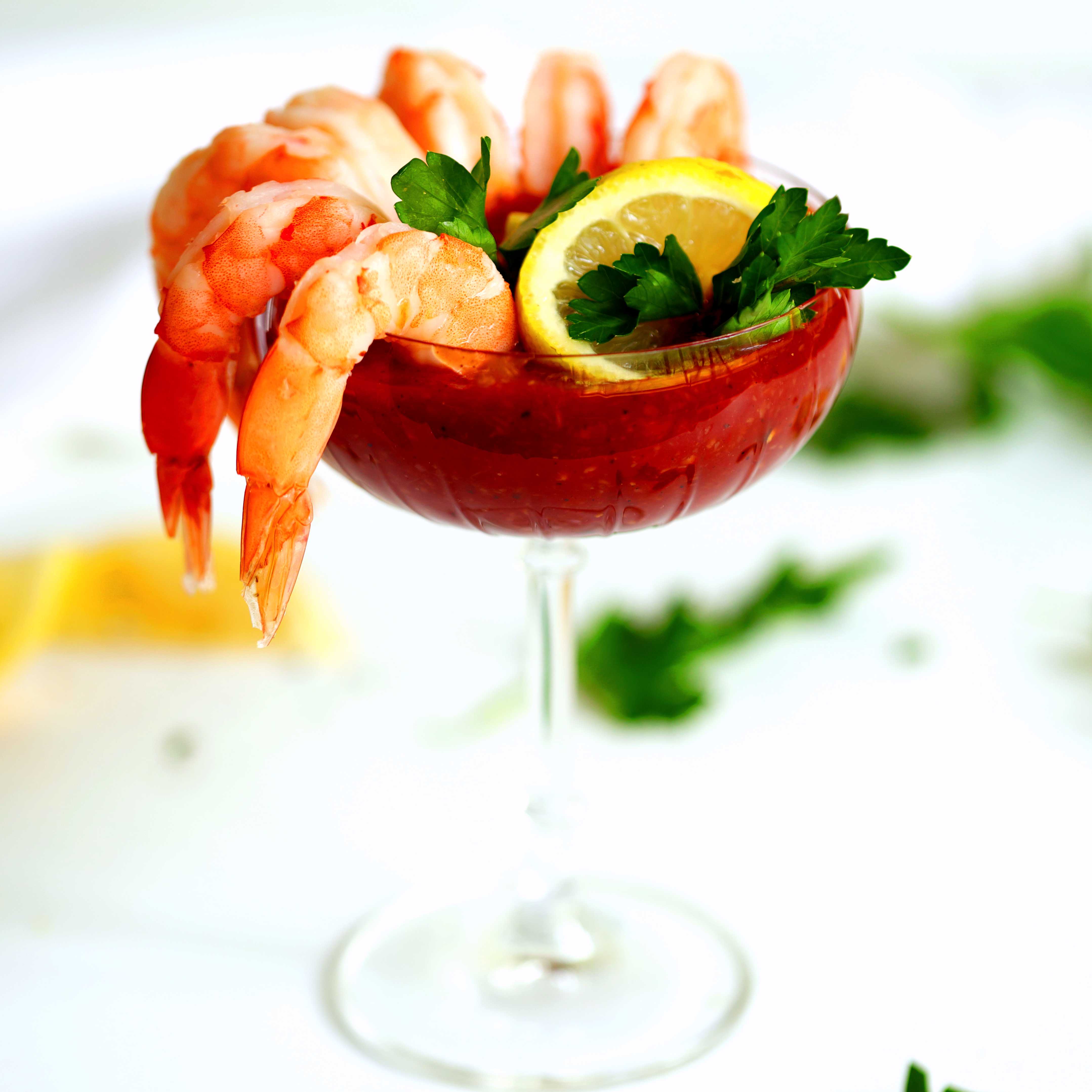 Shrimp Cocktail Sauce Recipe in a cocktail glass with shrimp, lemon, and cilantro