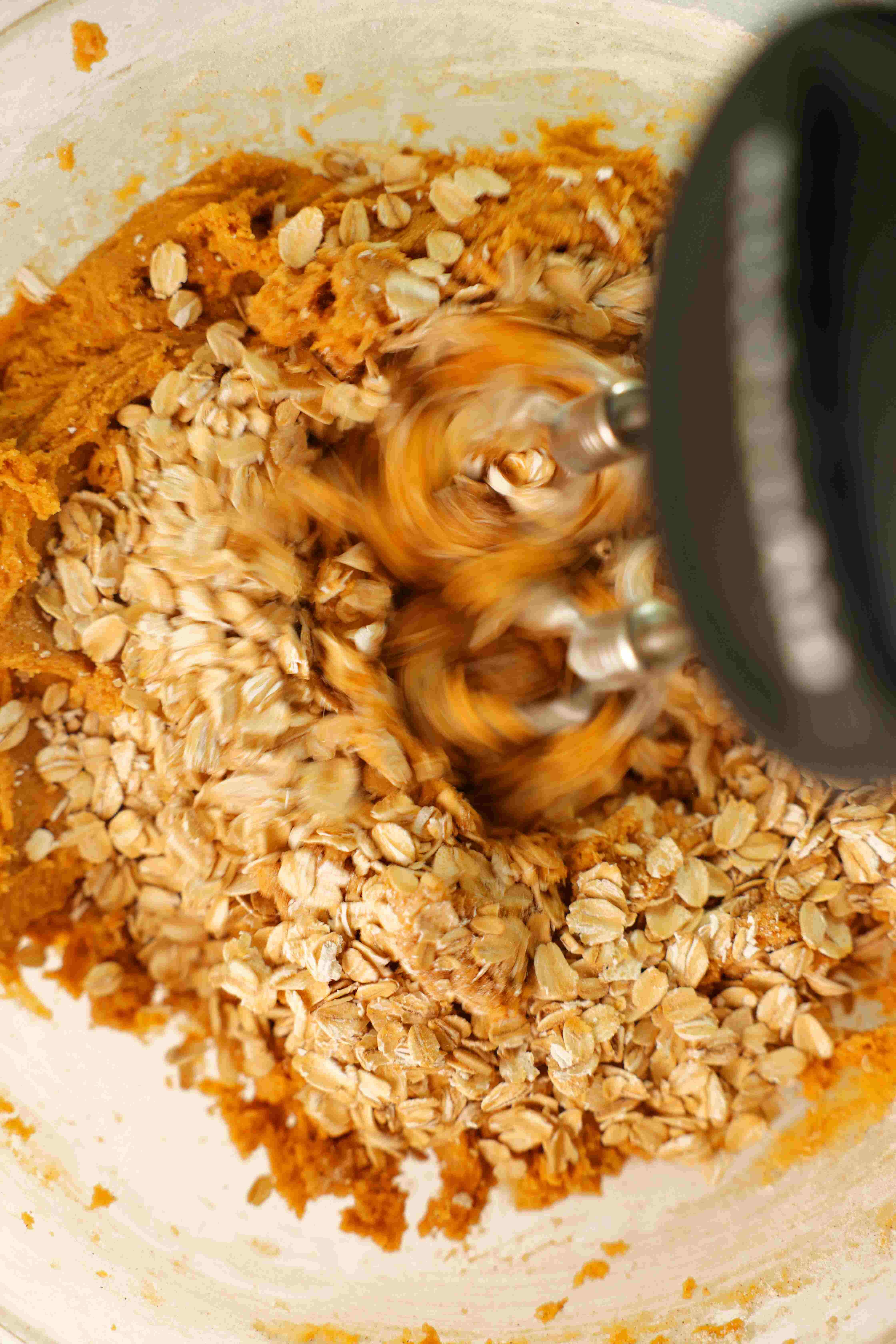 Stand-mixer combining oat and pumpkin puree in a mixing bowl.