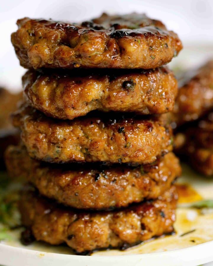 Stack of prepared Breakfast Sausage Recipe on a white plate with fresh thyme