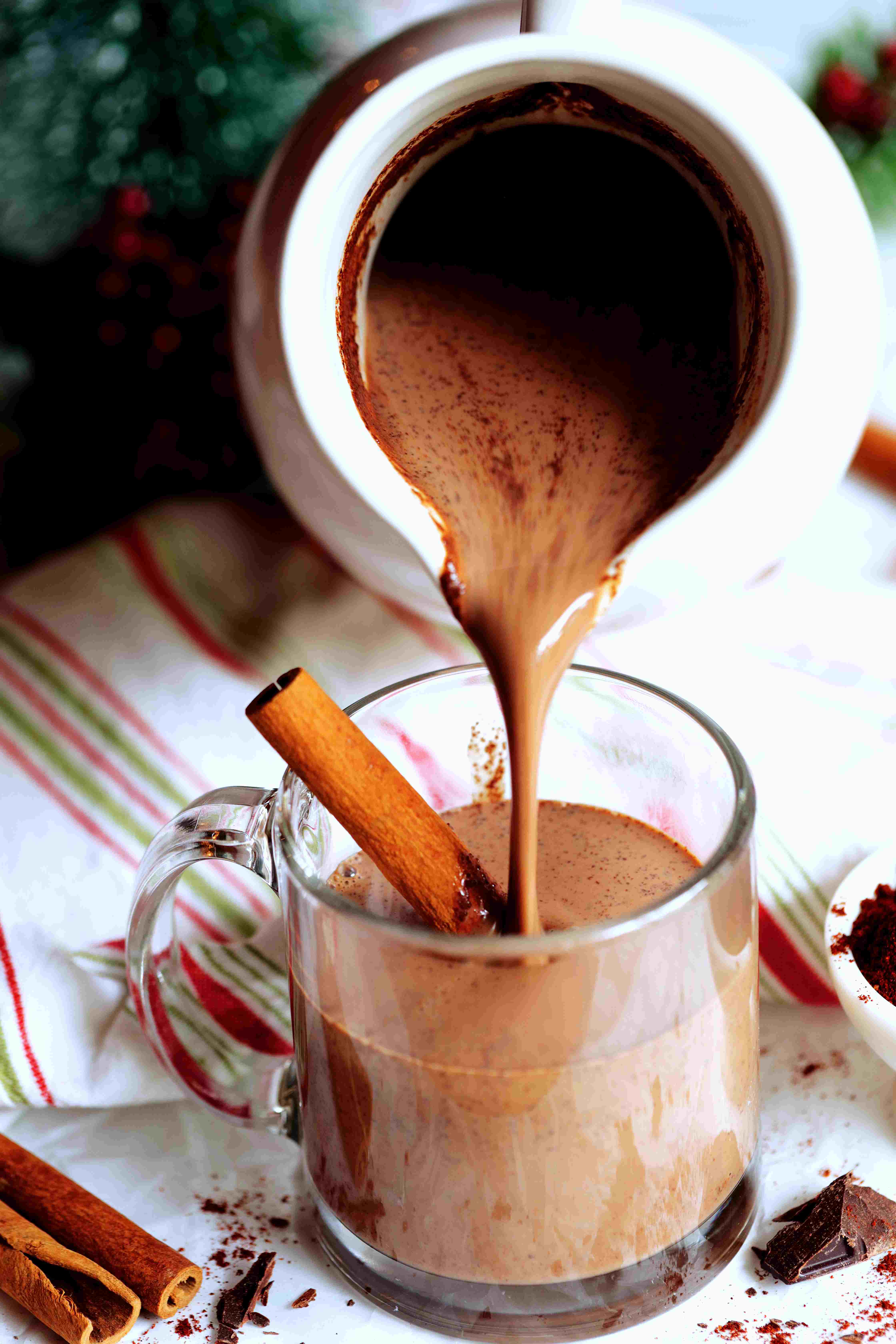 Mexican Hot Chocolate being poured into a mug with a cinnamon stick in it