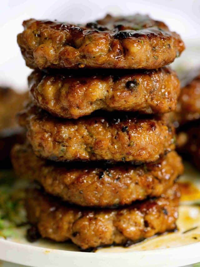 Prepared breakfast sausages on a white plate with fresh thyme