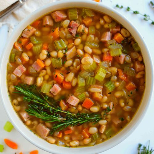 Prepared Navy Bean Soup topped with a sprig of rosemary
