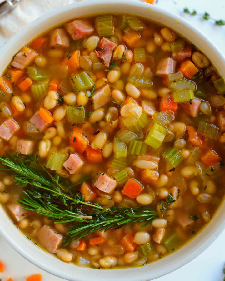 Prepared Navy Bean Soup topped with a sprig of rosemary