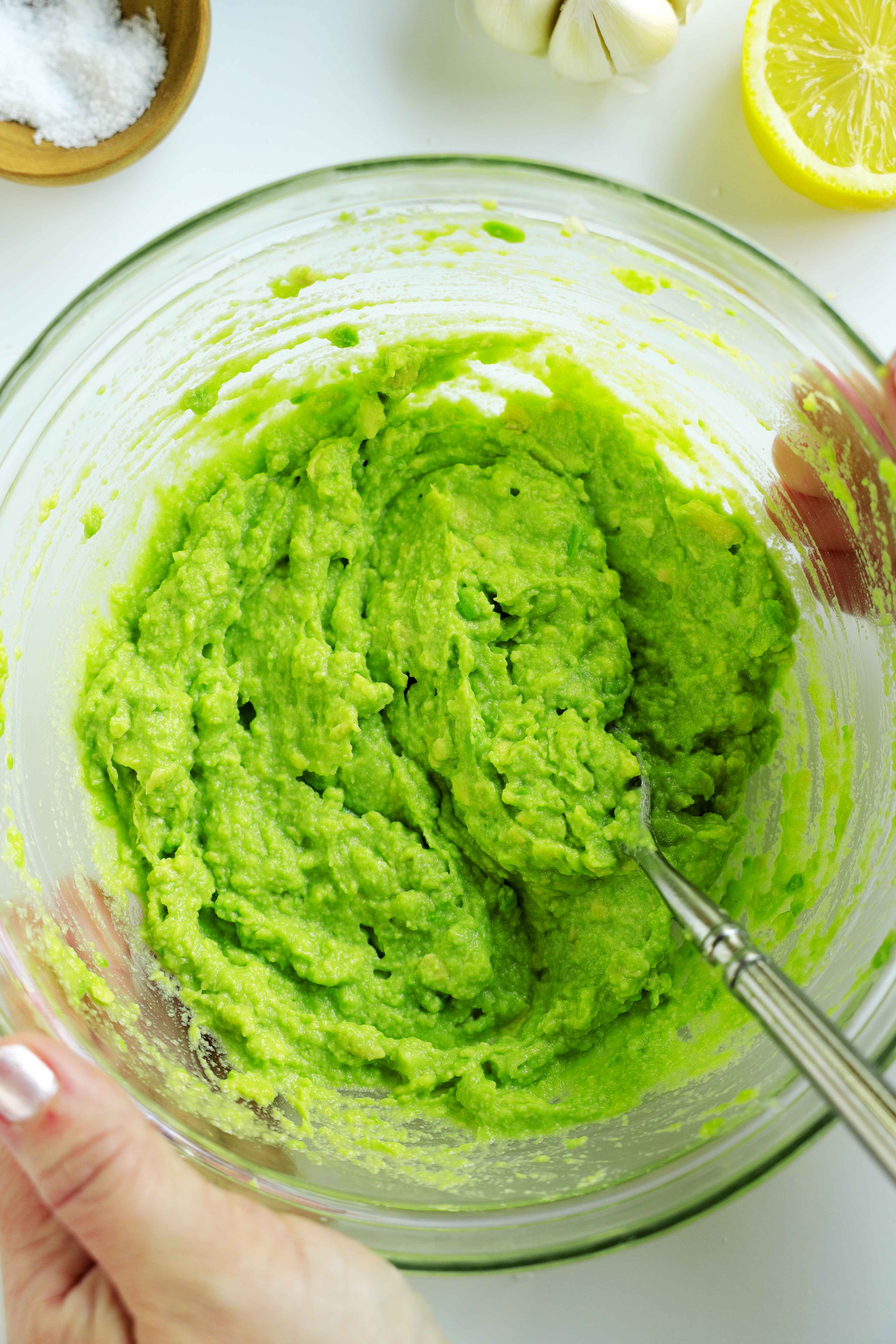 Overhead shot of creamy Avocado Spread in a clear mixing bowl