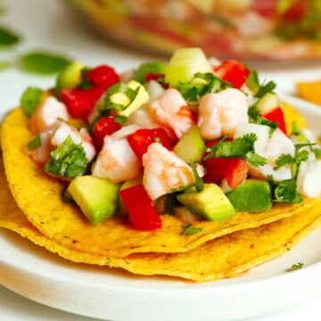 Ceviche de Camaron atop two corn tortillas next to a clear mixing bowl of more Ceviche de Camaron