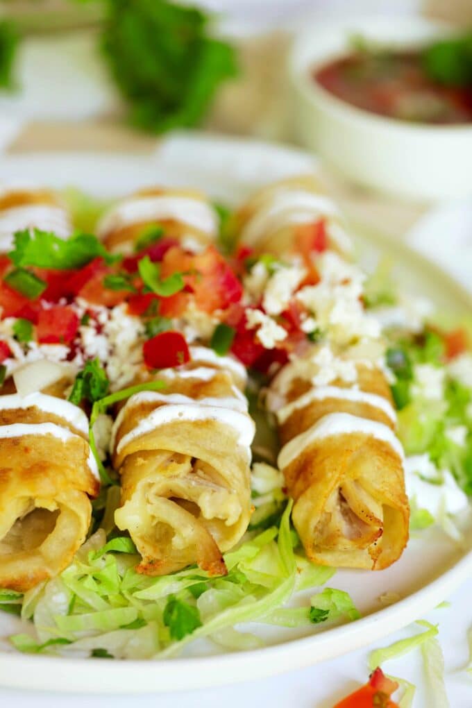 Three Flautas de Pollo with iceberg lettuce, sour cream, pico de gallo, and fresh cilantro