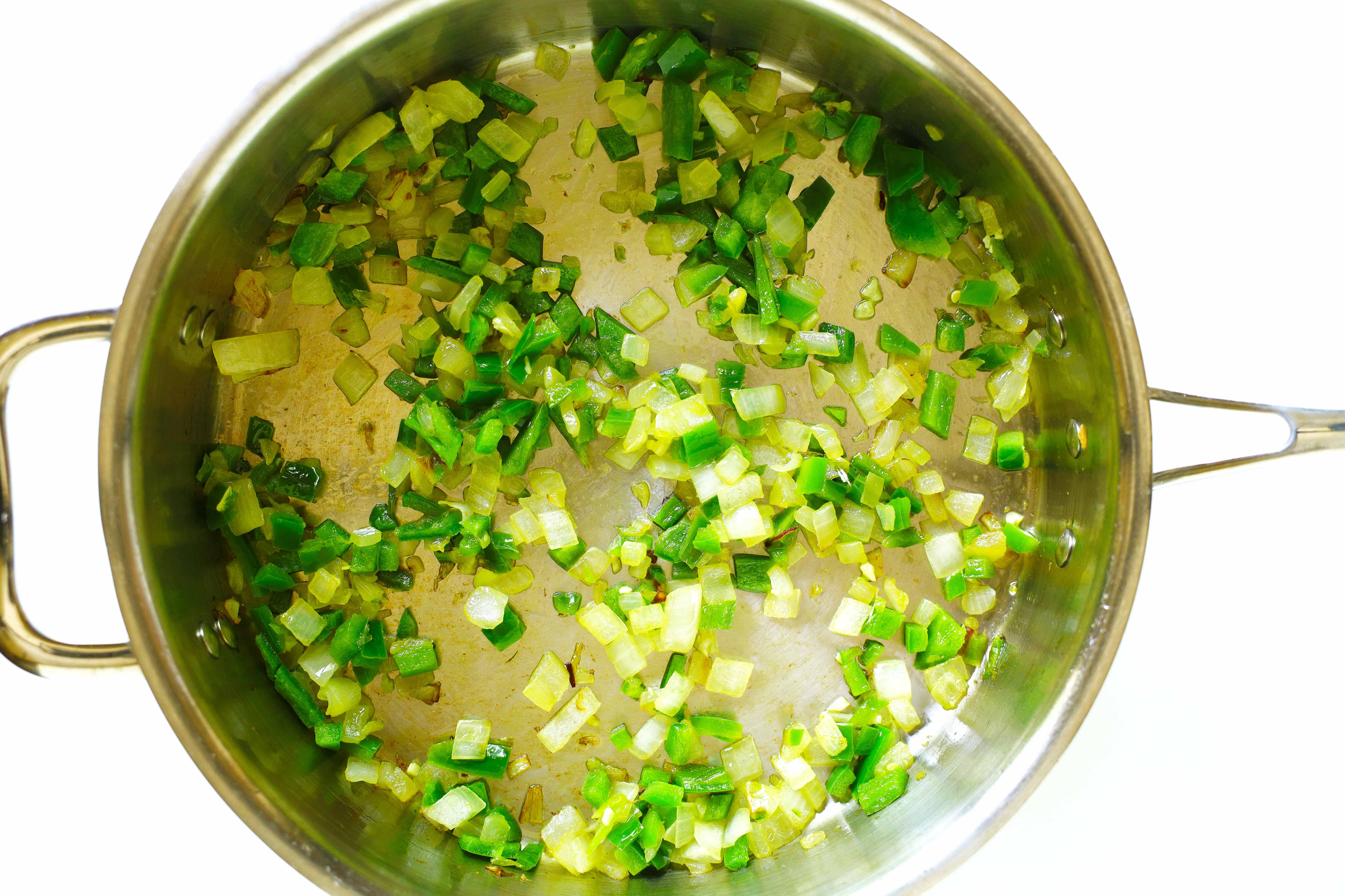 Diced onion and jalapeño cooking in a skillet.