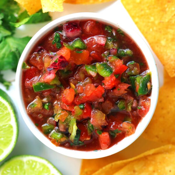 Overhead shot of homemade Salsa Fresca in a dipping bowl served with tortilla chips, lime halves, and fresh cilantro