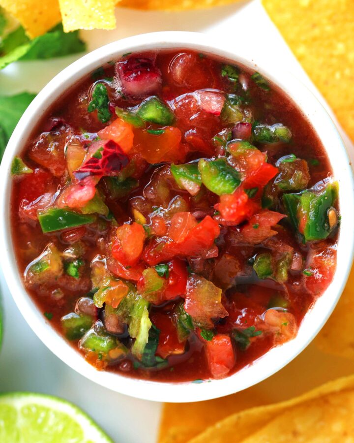 Overhead shot of homemade Salsa Fresca in a dipping bowl served with tortilla chips, lime halves, and fresh cilantro