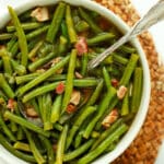 Slow cooker green beans with bacon in a white bowl with serving spoon