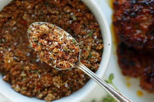 Breakfast sausage seasoning mixed up in a bowl with spoon being lifted above the bowl.