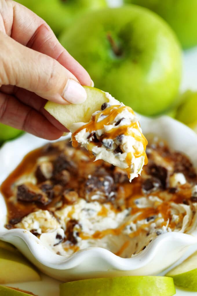 Caramel Apple Dip in a white scalloped serving bowl with green apples on the side