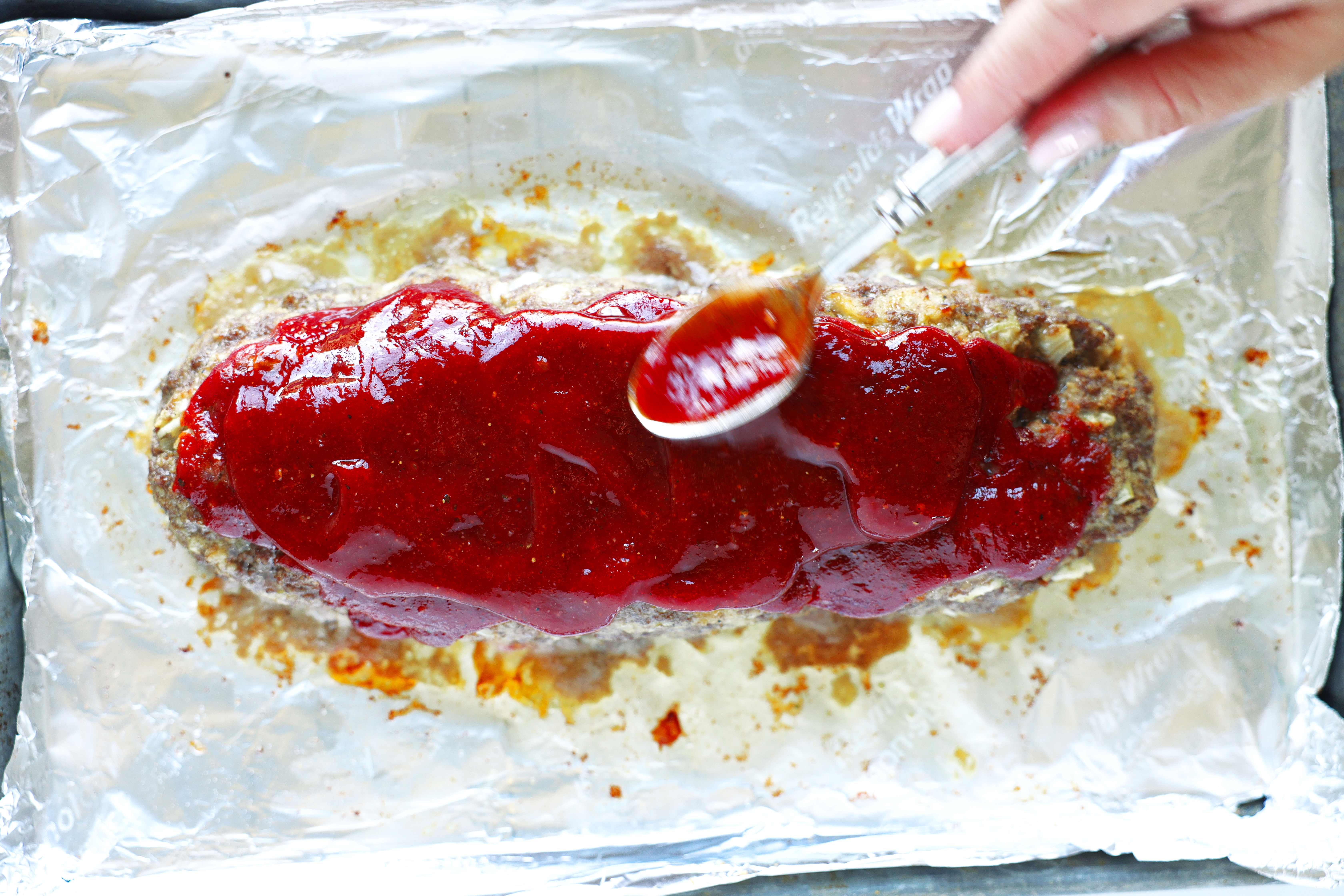 Spooning the topping on the uncooked meatloaf