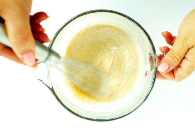 Whisking wet and dry ingredients together in a mixing cup for brioche French toast