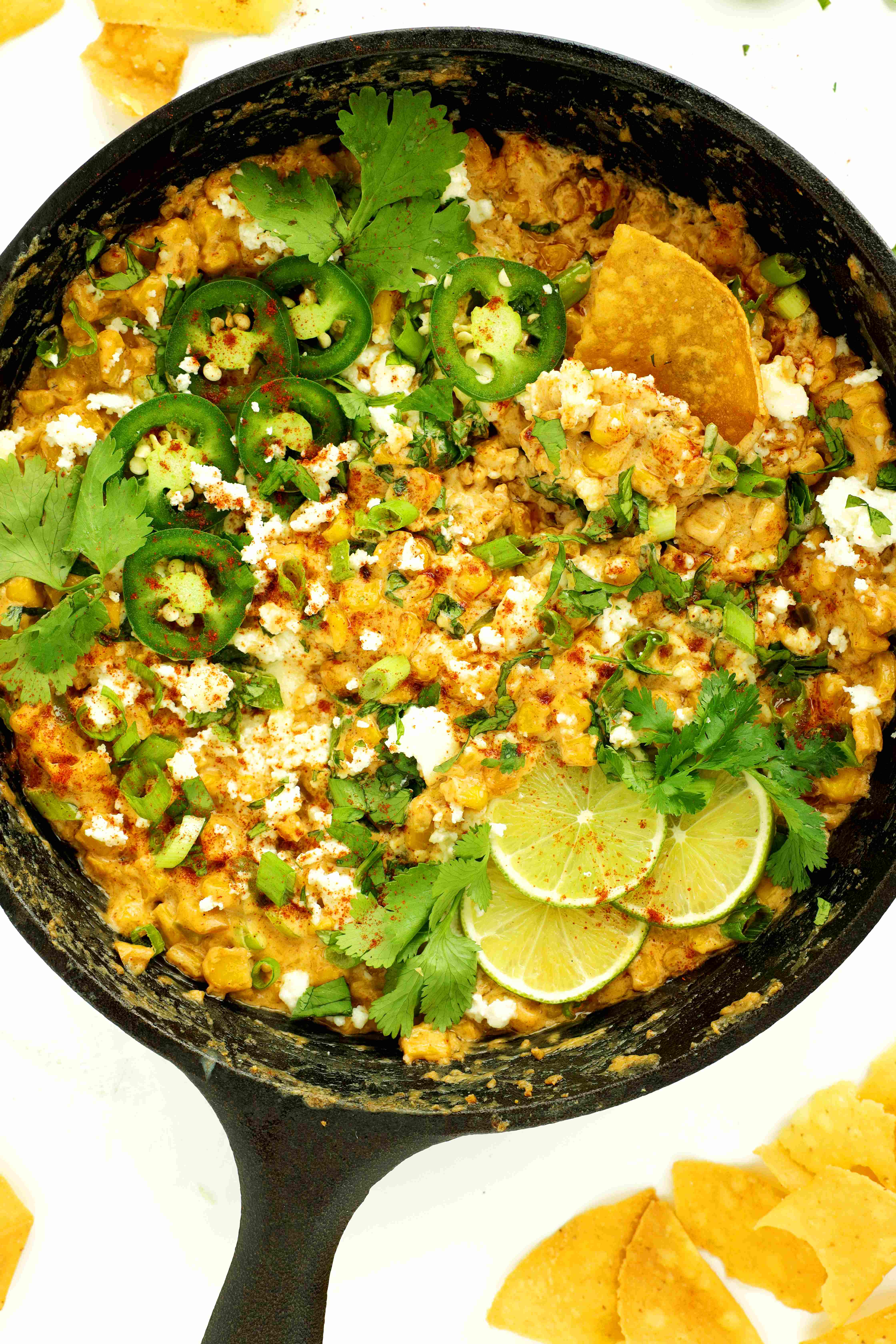 Elote Dip in a cast-iron skillet with toppings